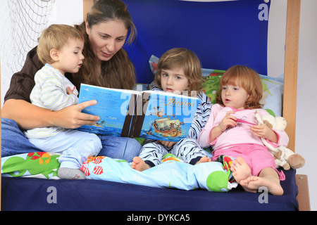 Madre la lettura di un libro che parla di pirati per i suoi figli in un Billi-Bolli loft bed Foto Stock