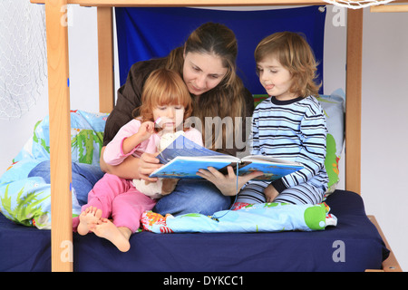Madre la lettura di un libro ai suoi daugter in un loft Billi-Bolli letto, Foto Stock
