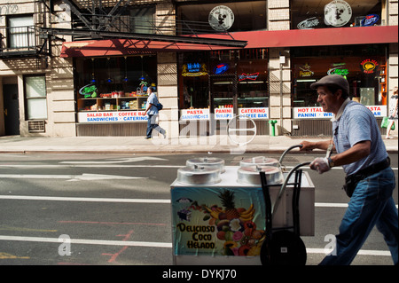 Un uomo / fornitore di prodotti alimentari spingendo un push style food cart in Little Italy, New York City Foto Stock