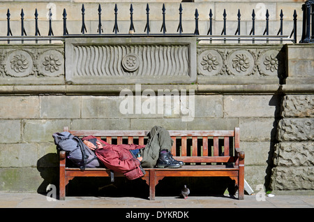 Un vagabondo addormentato su una panchina nel centro di Edimburgo. Foto Stock