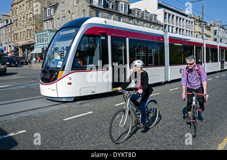 Un tram di Edimburgo passando dai ciclisti su Princes Street, Edimburgo, Scozia, Regno Unito. Foto Stock