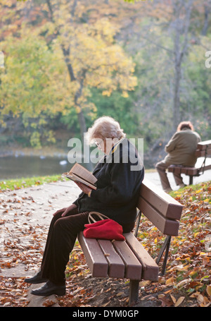 Due donne siedono sulle panchine in un parco. Foto Stock