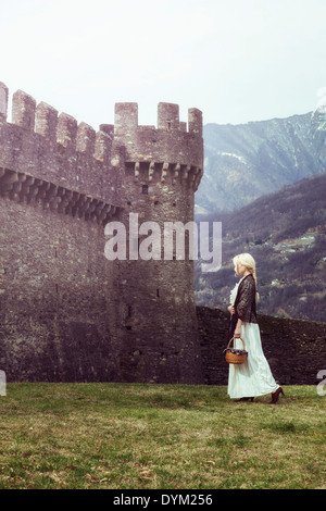 Una donna in un periodo bianco vestito è camminare lungo un castello Foto Stock