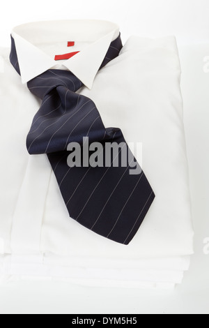 Pila di abito bianco Shirt con strisce rosse cravatta su sfondo bianco. Moderno concetto di business. Foto Stock