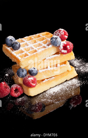 Deliziosi waffles con mirtilli, lamponi e more isolati su sfondo nero. Lussuoso sfondo dessert. Foto Stock