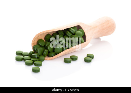 Green clorella e spirulina pillole sul convogliatore di legno isolato su sfondo bianco. Verde sano integratore alimentare concetto. Foto Stock