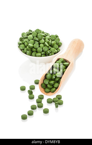 Pillole di verde in un recipiente e sul convogliatore di legno. A base di erbe naturali medicina alternativa. Chlorella, Spirulina, erba di frumento e di orzo erba Foto Stock