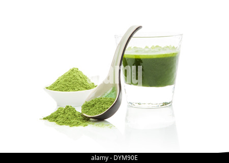 Erba di frumento polvere sul cucchiaio, verde orzo succo di erba in vetro isolato su sfondo bianco con la riflessione. Organici naturali hea Foto Stock
