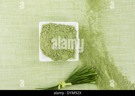 Massa Wheatgrass e le lame su sfondo verde, vista dall'alto. Verde super. A base di erbe salutari medicina alternativa. Foto Stock