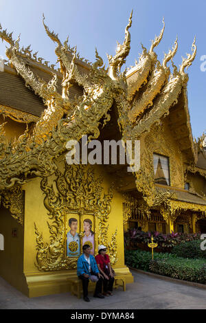 Turisti che si siedono di fronte al wc dorato casa a Wat Rong Khun, bianco tempio, dall'architetto Chalermchai Kositpipat Foto Stock