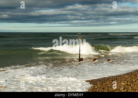 GROYNE SULLA SPIAGGIA DI FINDHORN MORAY con le onde che si infrangono sulla ghiaia Foto Stock