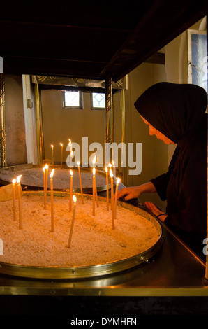 Nun accendendo candele presso il monastero di San Gerasimus, Cefalonia, Grecia Foto Stock