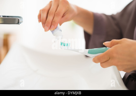 Primo piano sul giovane donna spremitura di dentifricio su uno spazzolino da denti Foto Stock