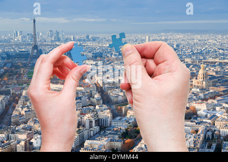 Maschio e femmina mani con piccoli pezzi di un puzzle con il distretto di Parigi e la Torre Eiffel sullo sfondo Foto Stock