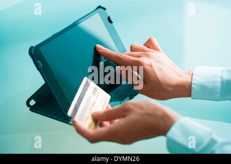 Donna shopping su internet utilizzando un tablet pc e carta di credito Foto Stock
