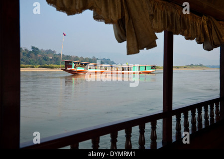 Vista orizzontale di un laotiano barca lenta fino il fiume Mekong in una giornata di sole. Foto Stock