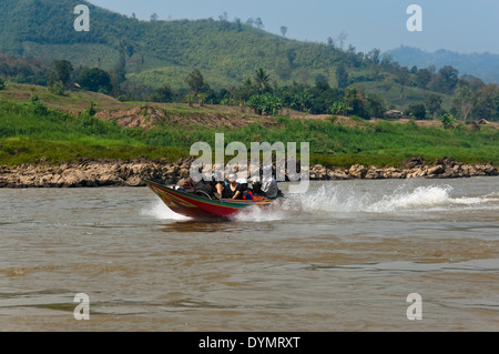 Vista orizzontale di un vivacemente colorato power boat con passeggeri accelerando lungo il fiume Mekong. Foto Stock