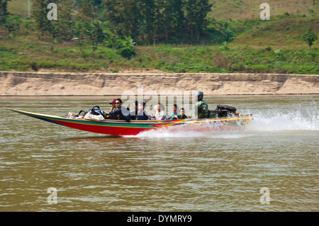 Vista orizzontale di un vivacemente colorato power boat con passeggeri accelerando lungo il fiume Mekong. Foto Stock