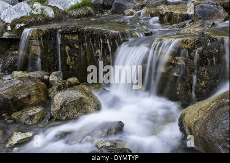 Ruscello di montagna che scorre su moss rocce coperte Foto Stock