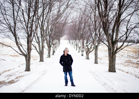 Giovane uomo sorge tra alberi in inverno Foto Stock