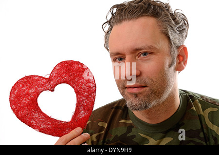 Soldato tenendo un cuore rosso forma su uno sfondo bianco Foto Stock