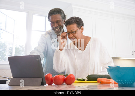 Coppia senior con tavoletta digitale in cucina Foto Stock