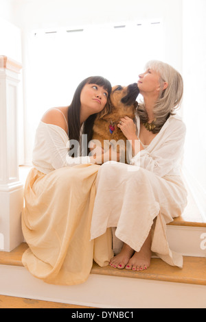 Madre e figlia abbracciando il cane sui passi Foto Stock