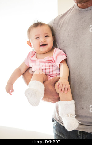 Padre che trasportano Laughing baby girl Foto Stock