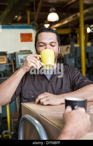 Lavoratore di bere il caffè in magazzino Foto Stock