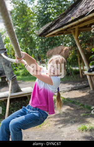 Ragazza caucasica appeso su funi all'aperto Foto Stock