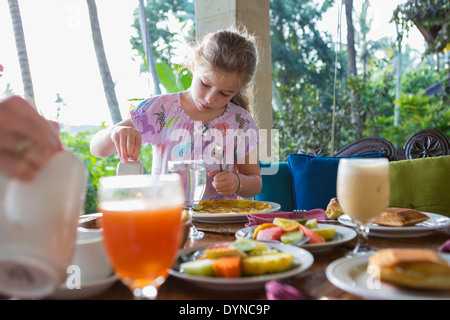 Ragazza caucasica gustando la prima colazione sul patio Foto Stock