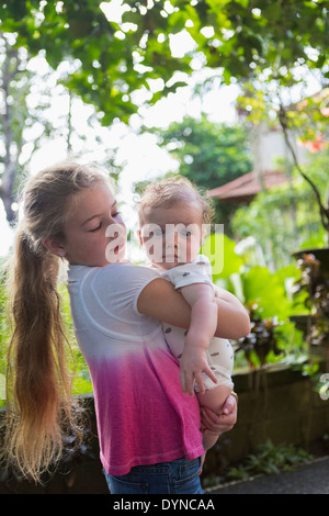 Ragazza caucasica portando baby boy nel giardino tropicale Foto Stock