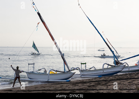 Pescatore tira in barca a vela la linea sulla spiaggia Foto Stock