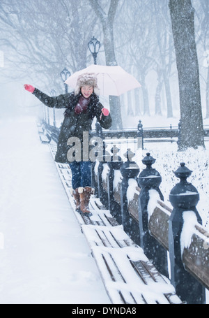 Donna asiatica camminando sulle panchine in presenza di neve il Central Park di New York City, New York, Stati Uniti Foto Stock