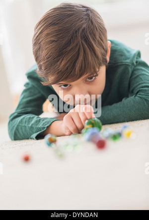 Ispanico ragazzo giocando con marmi sul pavimento Foto Stock