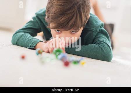 Ispanico ragazzo giocando con marmi sul pavimento della camera Foto Stock