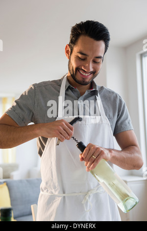 Razza mista uomo apertura bottiglia di vino Foto Stock