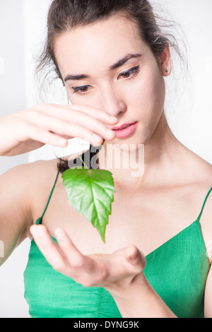 Donna che guarda stupito a foglia verde fluttuanti nell'aria. Immagine concettuale dell ambiente e la meraviglia della natura. Foto Stock