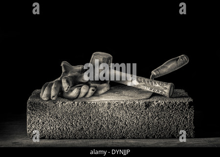 Builder mattone cazzuola, martello forfettaria e guanti in appoggio su un blocco di cemento armato. Foto Stock