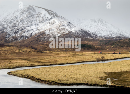 Il tetto rosso di un BOTHY contro montagne coperte di neve in Glen Affric Scozia durante i primi anni di primavera Foto Stock