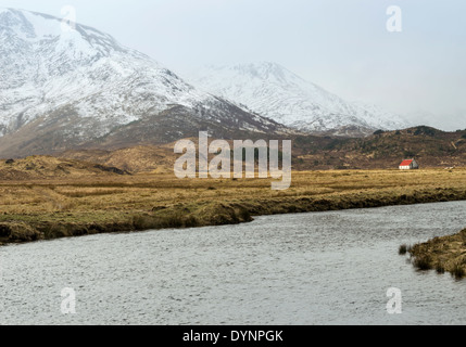 Montagne coperte di neve e casa o BOTHY con un Tetto Rosso in Glen Affric Scozia Scotland Foto Stock