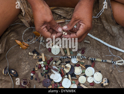Donna boscimane facendo collane con uovo di struzzo Shell, Tsumkwe, Namibia Foto Stock