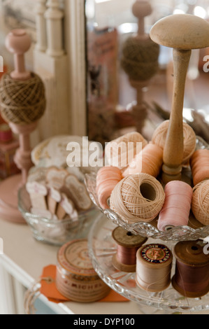 Vintage di bobine di cotone nei toni del rosa e pesca in un supporto a più livelli Foto Stock