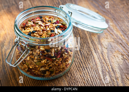 Muesli fatti in casa in aprire il vasetto di vetro sul rustico sfondo di legno Foto Stock