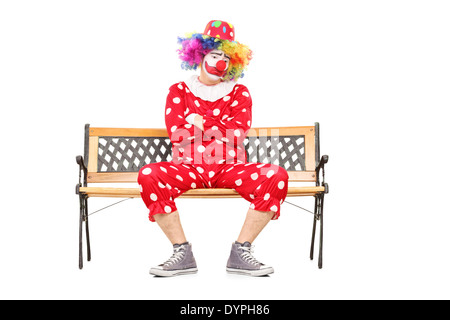 Infelice clown seduto su una panca in legno Foto Stock