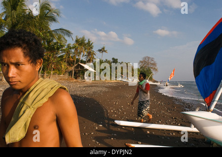 Alcuni pescatori prendere le loro barche a terra vicino alla Spiaggia di Amed, un villaggio di pescatori nella parte Est di Bali. Amed è un litorale lungo st Foto Stock