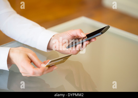 Donna shopping online utilizzando il telefono cellulare e una carta di credito .indoor.close-up Foto Stock