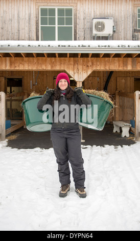 Un giovane e fiero agricoltore holding secchi pieni di fieno. Foto Stock