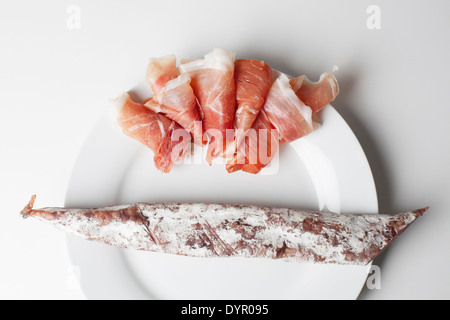 Prosciutto Spagnolo e fuet insaccato su una piastra bianca Foto Stock