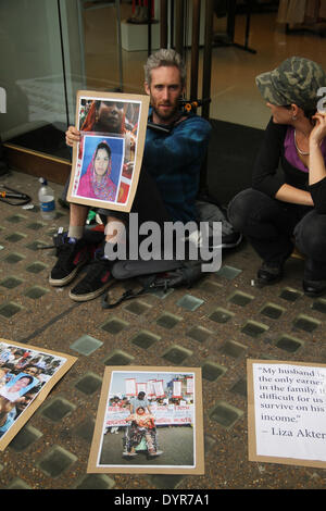 Londra, Regno Unito. Il 24 aprile 2014. Un manifestante con il suo collo incatenati sulle porte di vetro della Oxford Street store. La protesta ha cominciato a 8.30. concatenate a collo alto sulle porte di vetro della Oxford Street store. Le etichette di Benetton sono stati trovati in fabbrica, ma nonostante questo i vestiti costruttori hanno rifiutato di maggio un risarcimento alle famiglie . Credito: David mbiyu/Alamy Live News Foto Stock